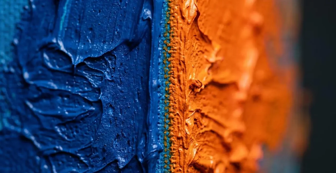 Abstract close-up of blue and orange paint meeting at a sharp boundary, creating optical tension and visual energy